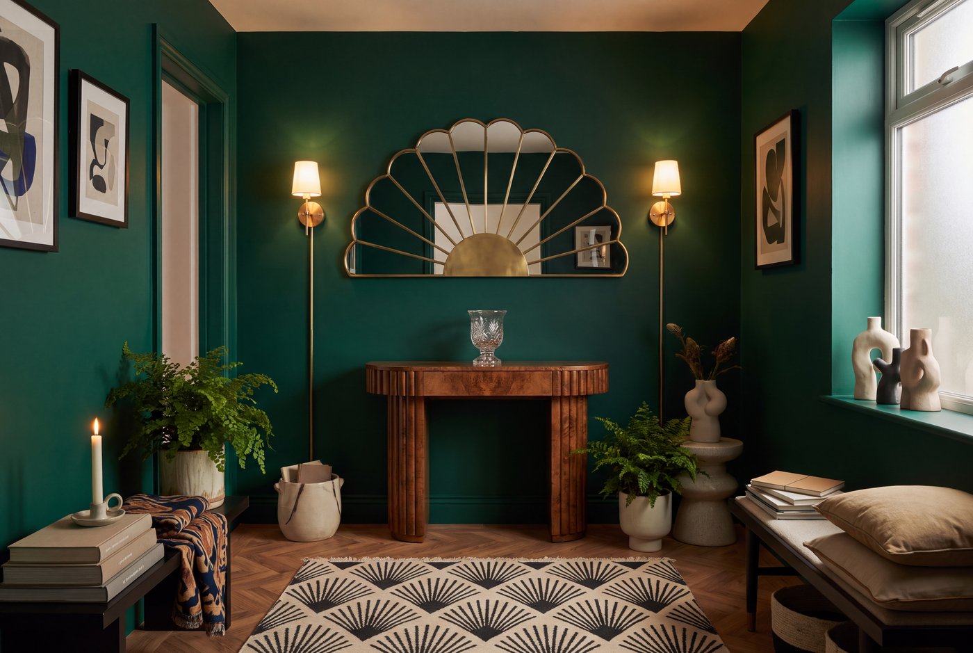 A small art deco entrance hall fully committed: a fan mirror, a pair of brass sconces, a geometric rug and a fluted console